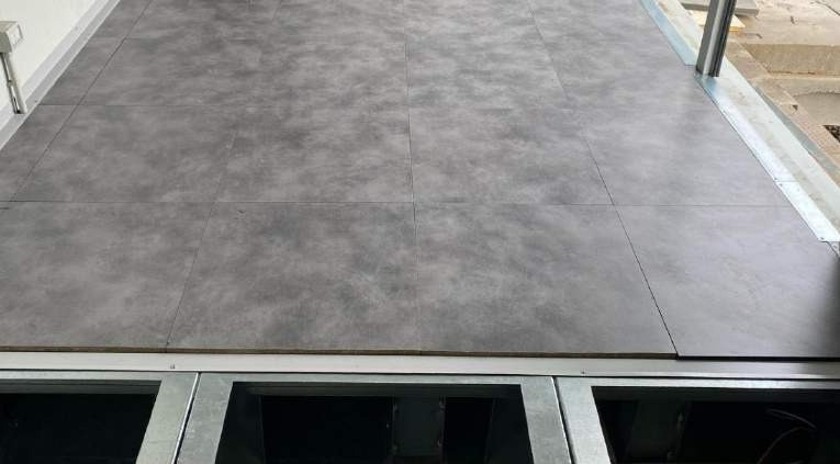 FlexEhouse raised micro-ceramic floor — serviceable panels on a galvanised steel support frame for cable access and climate control.