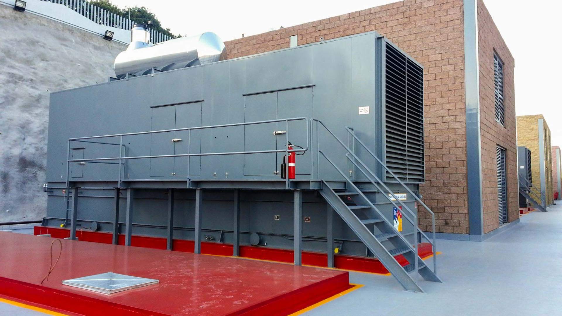 Elevated FlexEgen enclosure with maintenance walkway and rooftop exhaust silencer.