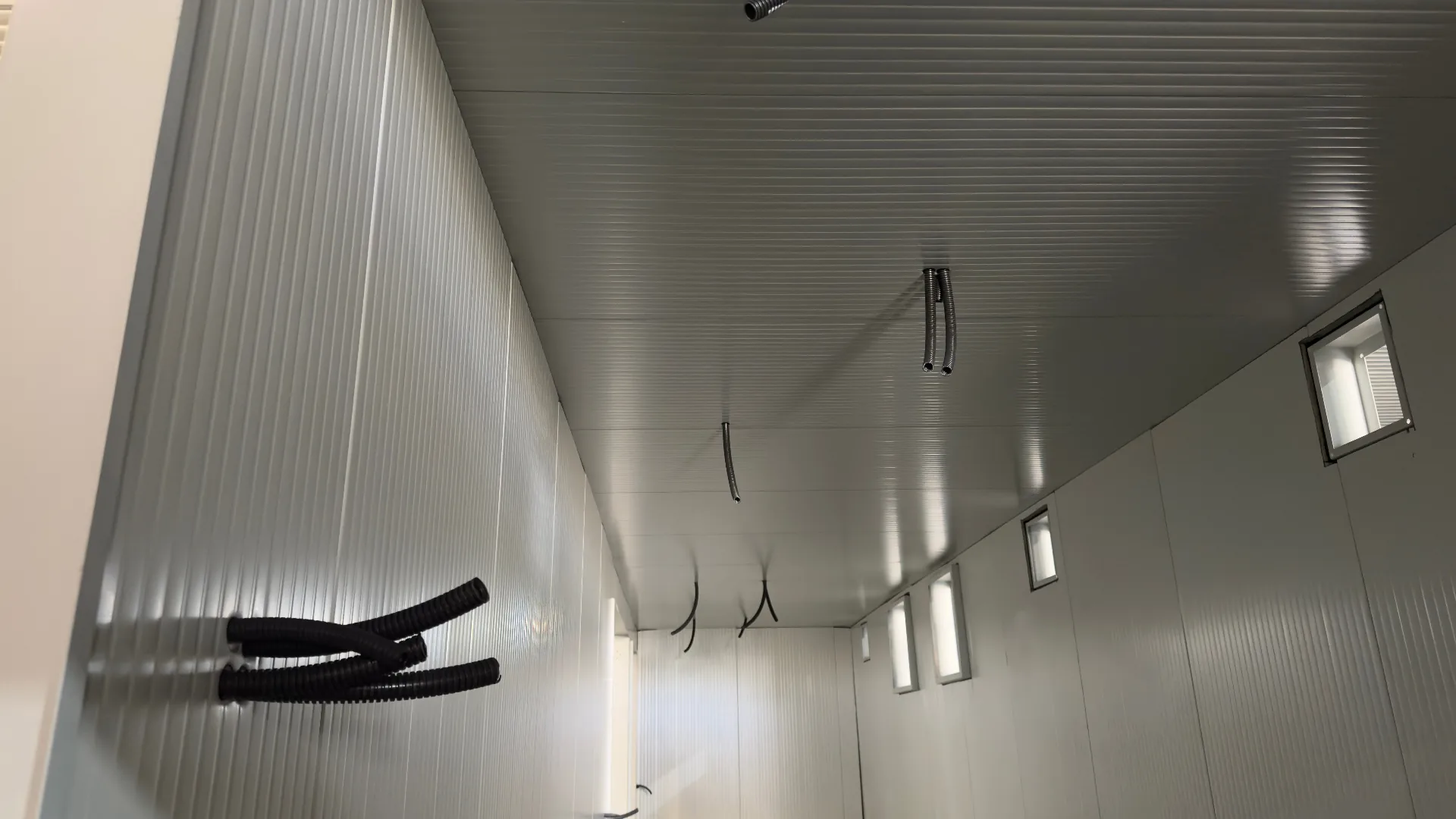 FlexEskid interior under fit-out — insulated wall and ceiling panels with pre-routed cable conduits and recessed LED lighting ready for equipment installation.