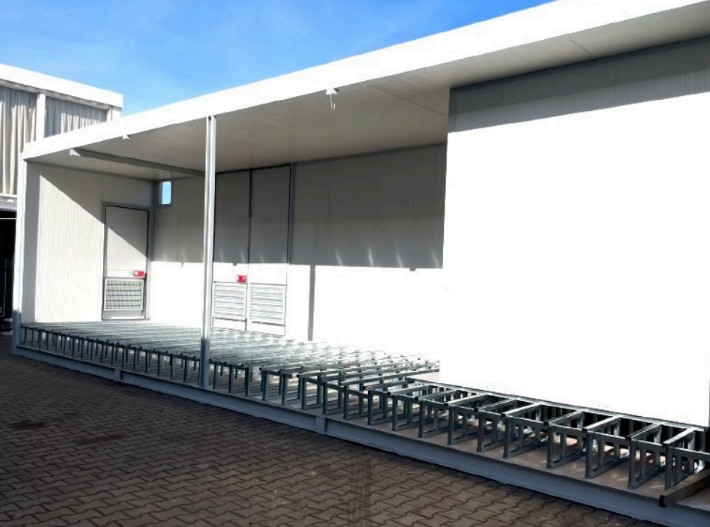 FlexEhouse on site — covered walkway with integrated cable tray supports, access doors and ventilation louvres beneath the canopy.