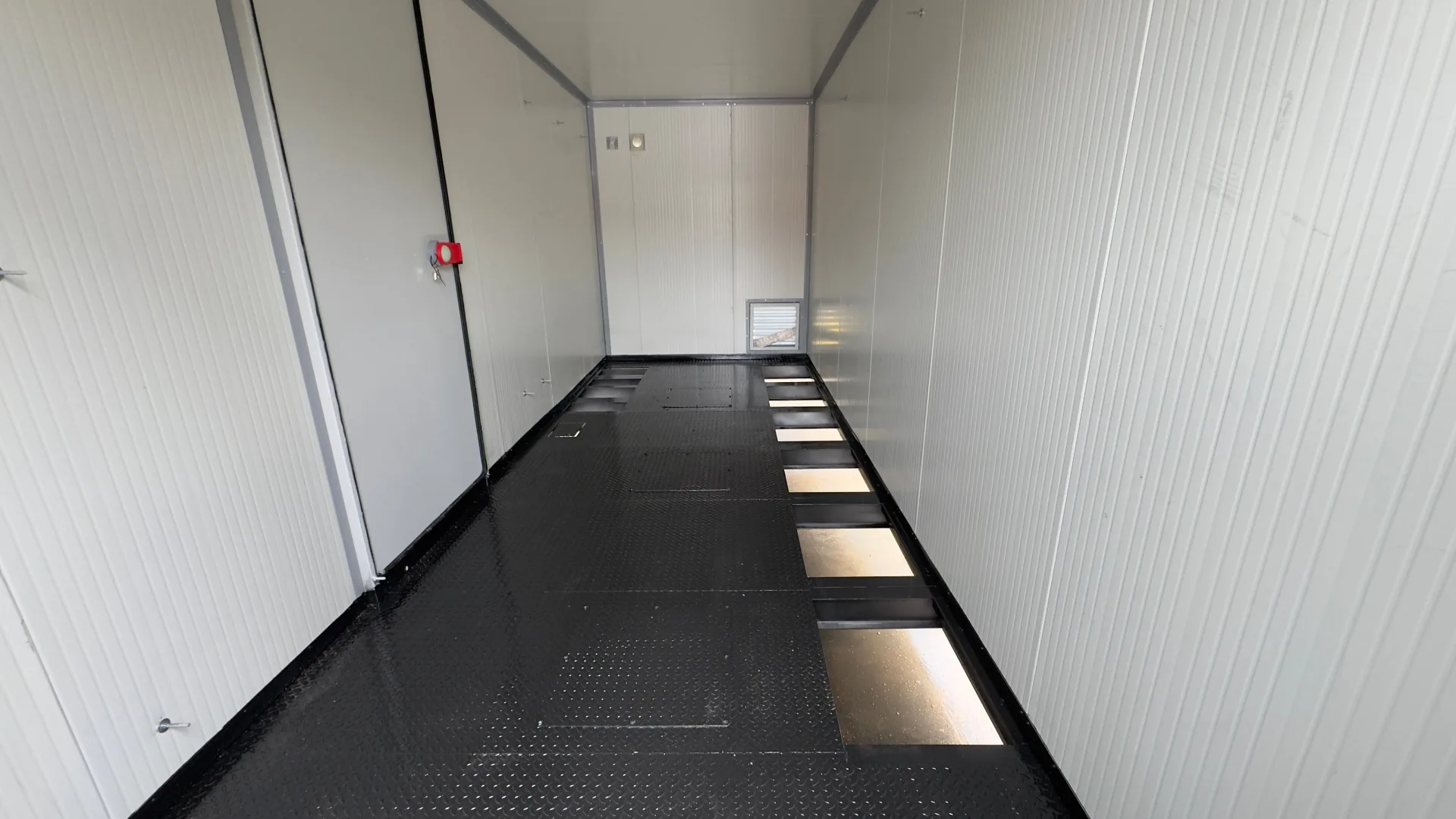 FlexEskid raised steel floor — chequer-plate panels on a structural support frame with cable access cut-outs for under-floor routing.
